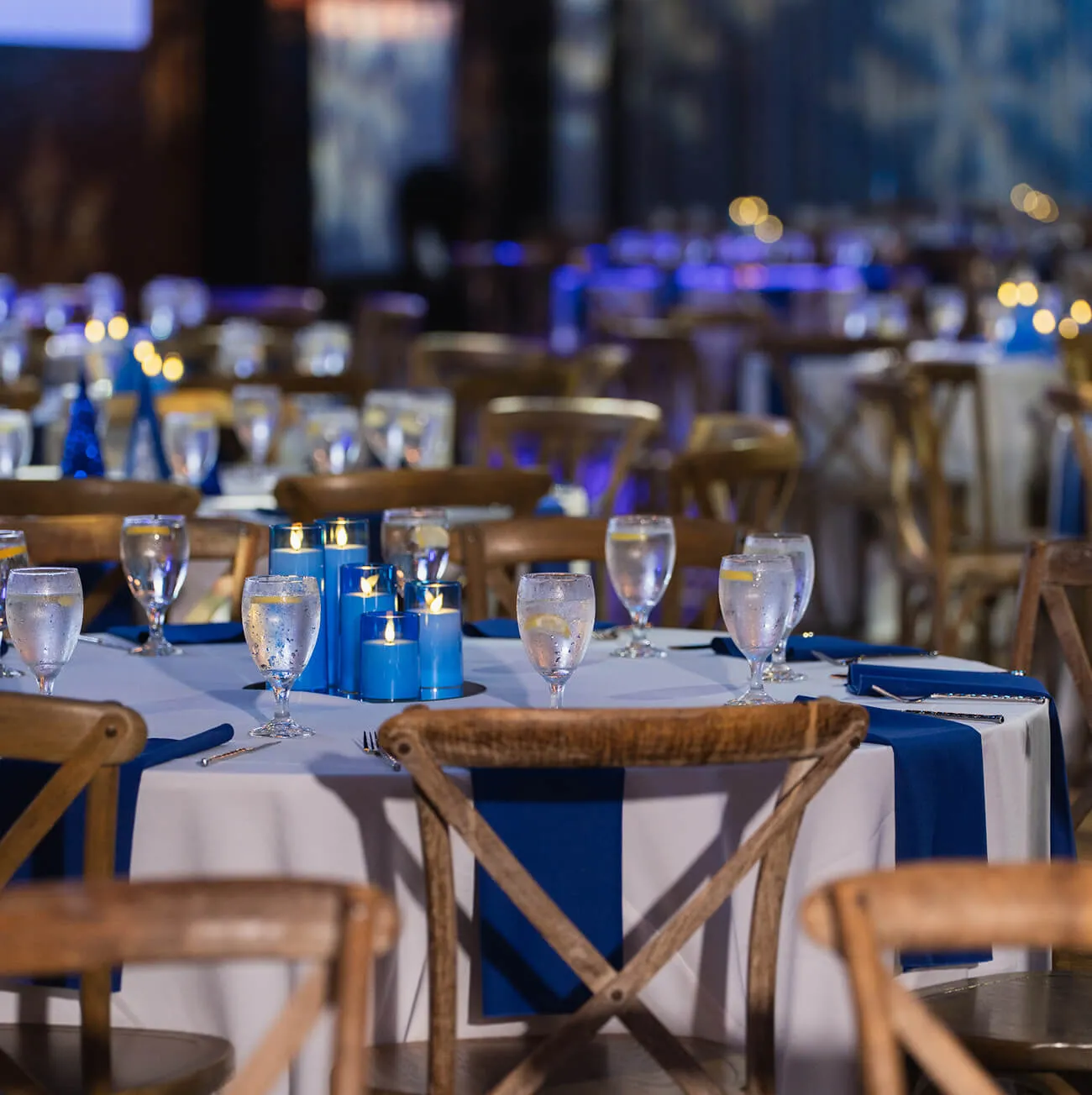 Elegant wedding reception table with blue candle centerpieces and cross-back chairs