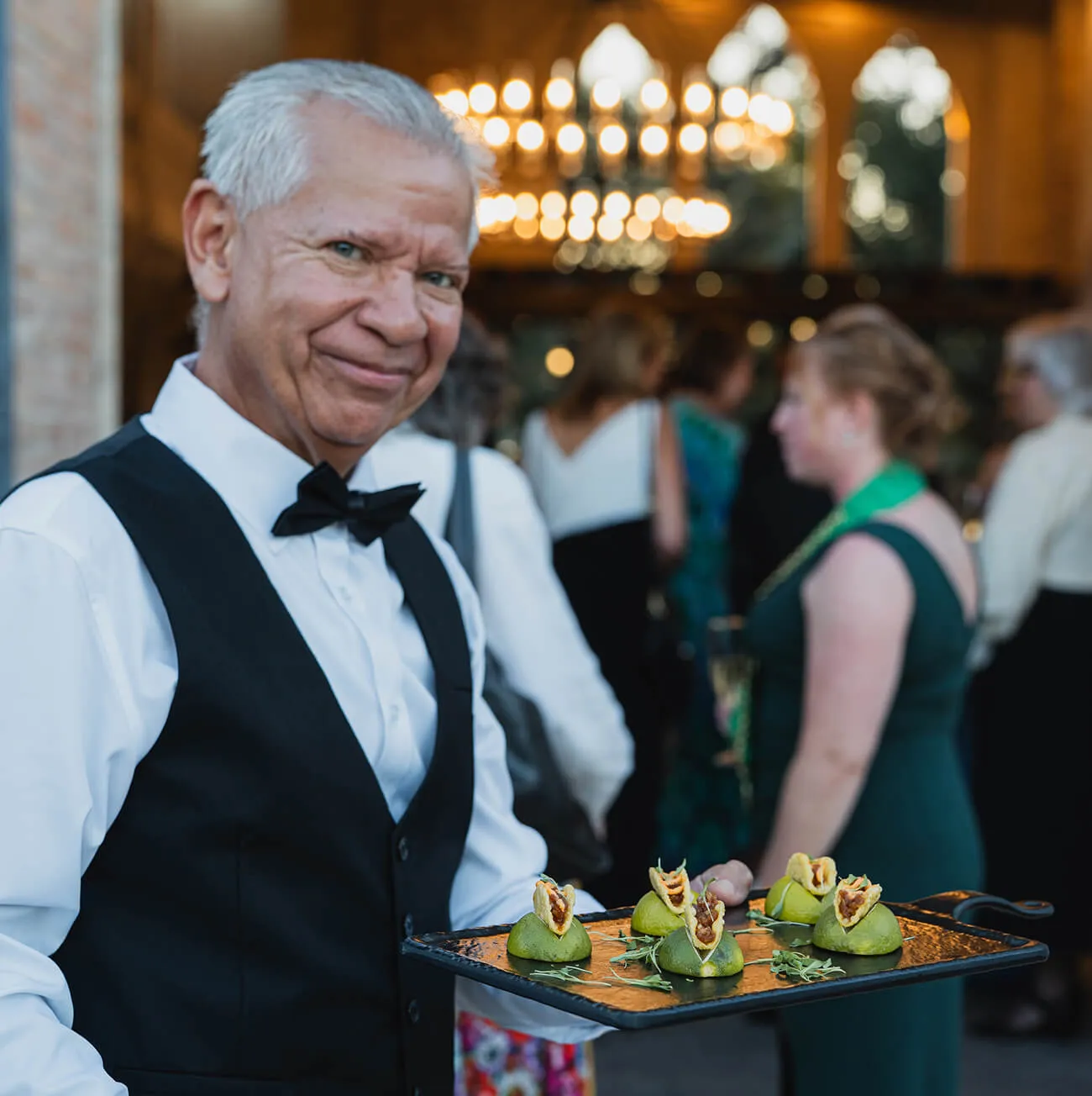 Server presenting passed appetizers on mini tacos served on lime halves