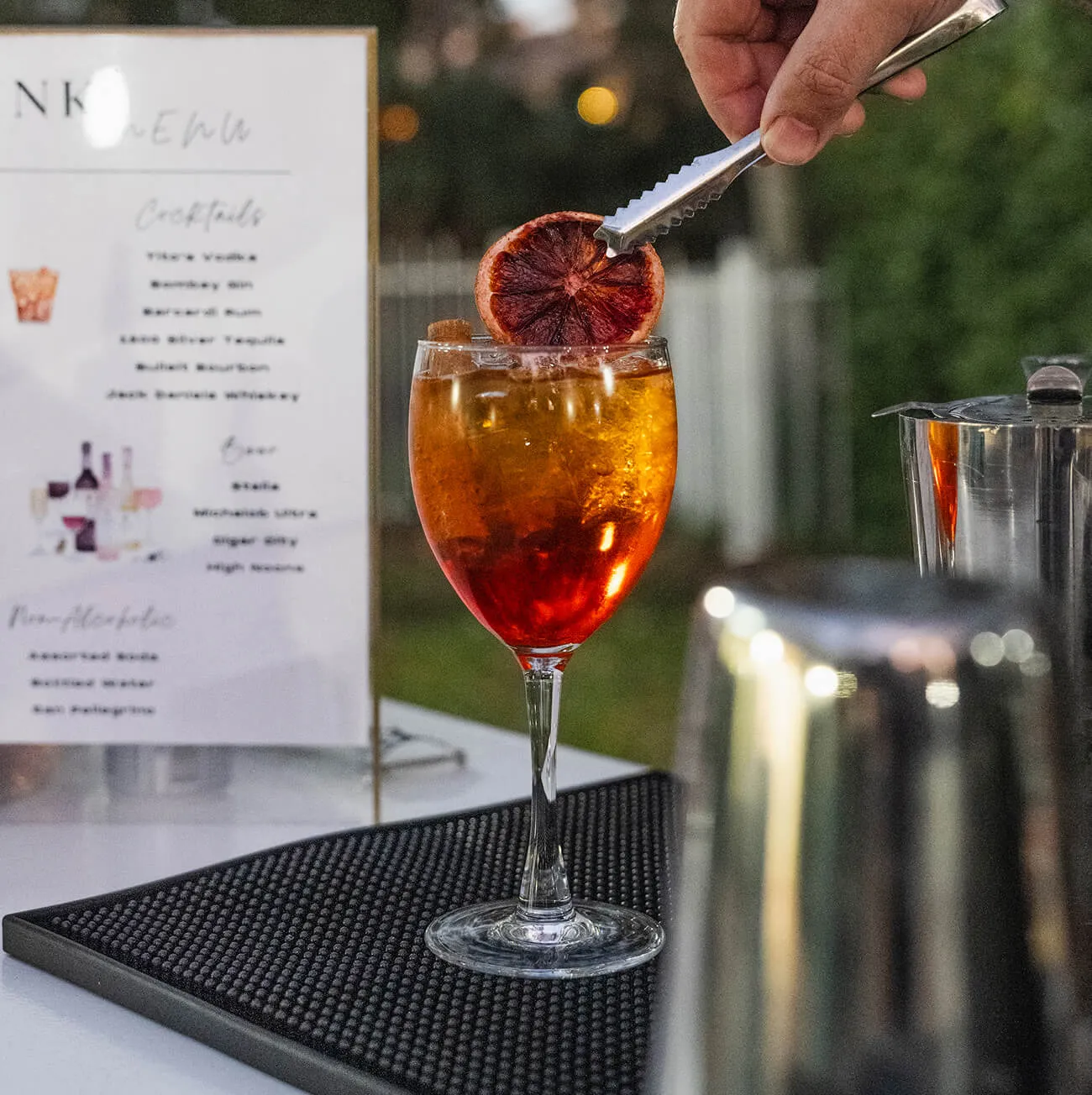 Bartender garnishing a signature cocktail with a dried blood orange slice