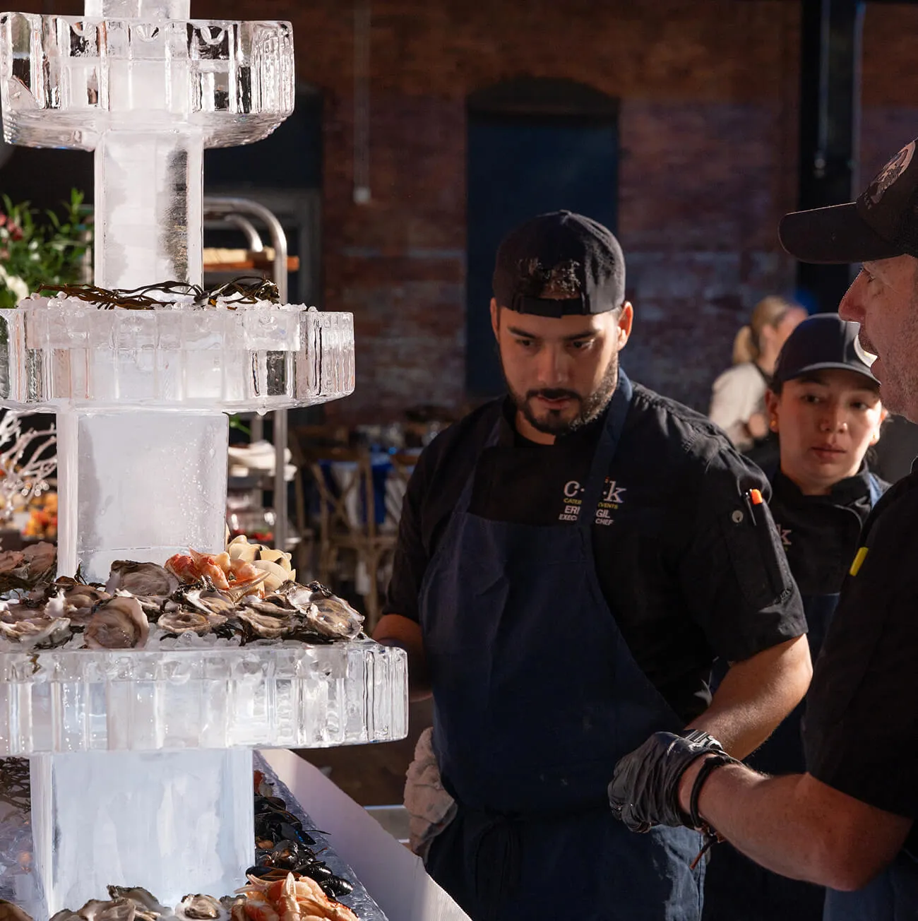 Chefs attending a multi-tiered ice sculpture seafood display with fresh oysters