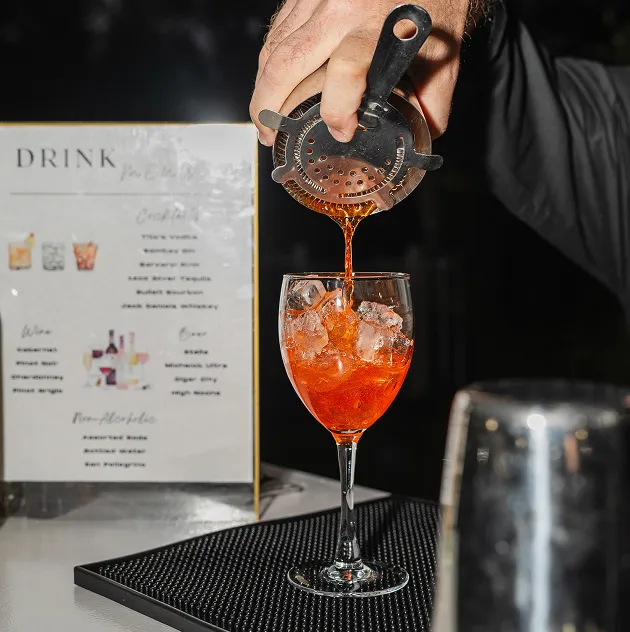Craft cocktail being poured over ice at an event bar