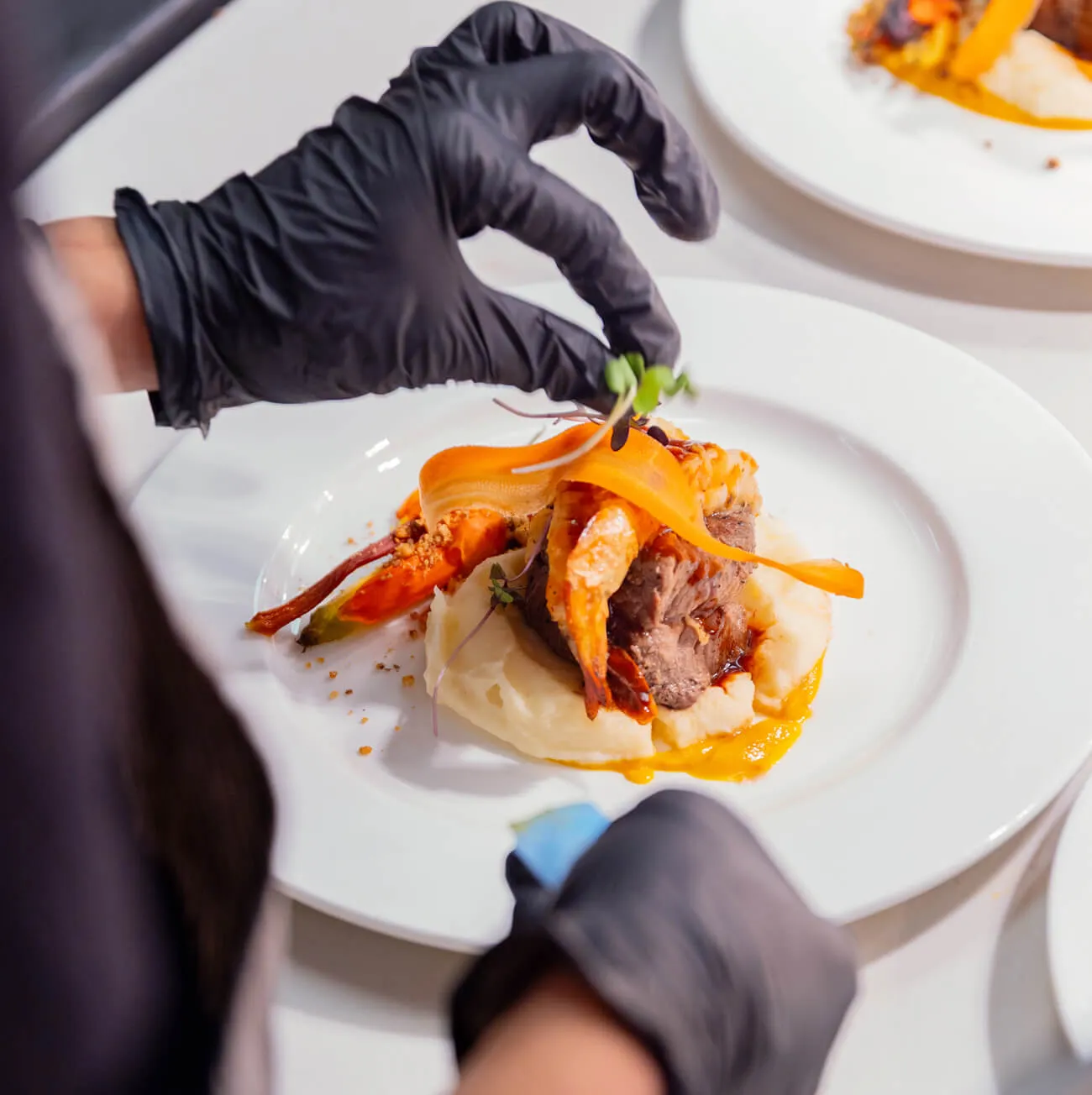 Chef carefully plating a composed entree with seasonal vegetables