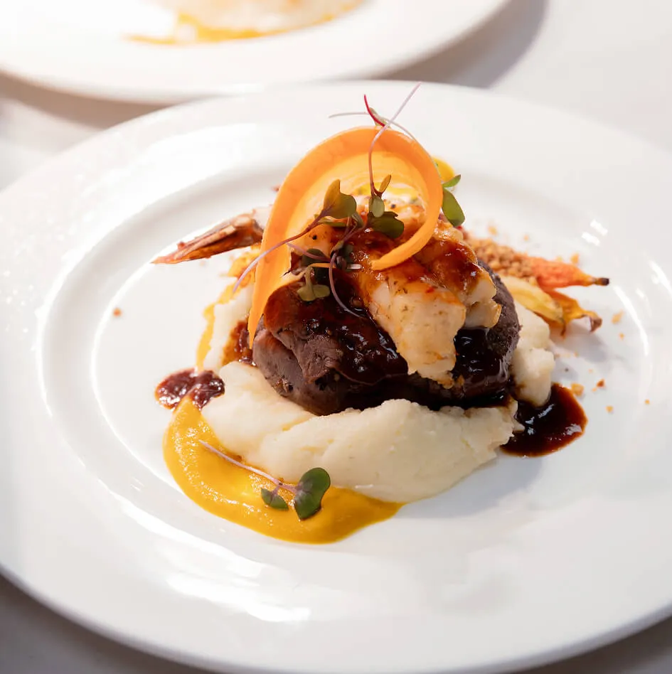 Chef carefully plating a composed entree with seasonal vegetables